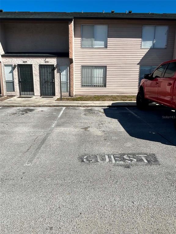 A two-story apartment building exterior features light-colored siding and a designated guest parking space — 4031 HENLEY ROAD UNIT 1706, ORLANDO, FL