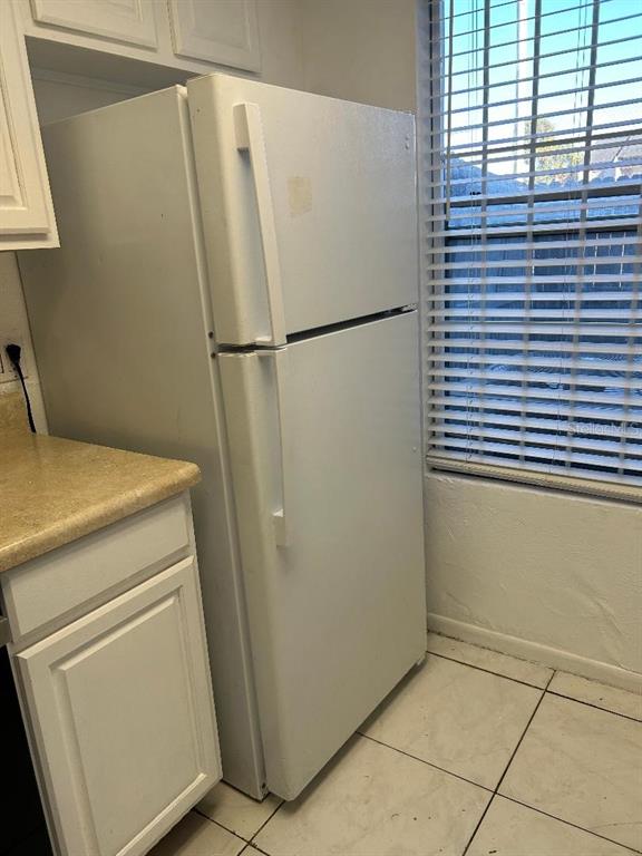 A white refrigerator stands in a kitchen with white cabinets, a countertop, and tiled flooring — 4031 HENLEY ROAD UNIT 1706, ORLANDO, FL