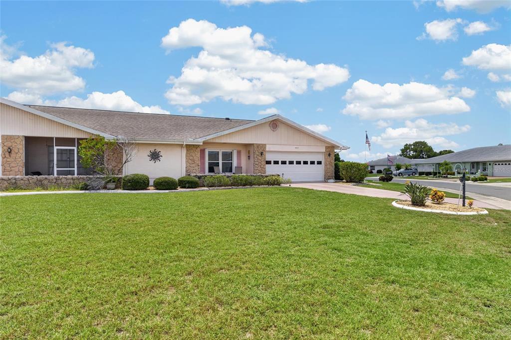 A single-story house with a beige exterior, stone accents, and a two-car garage — 907 BLUEWATER DRIVE, SUN CITY CENTER, FL