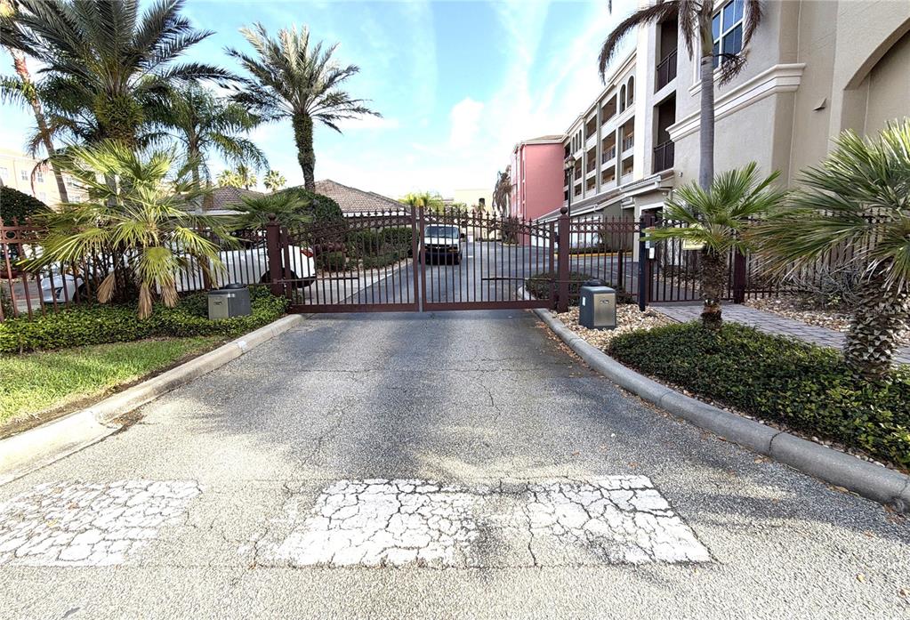 A gated entrance with a paved driveway leads to a multi-story apartment building — 424 LUNA BELLA LANE UNIT 416C, NEW SMYRNA BEACH, FL