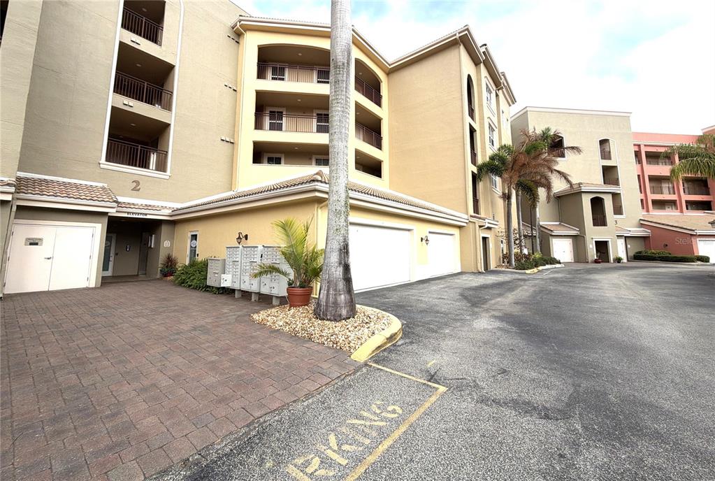 An exterior view of a multi-story apartment building with garages, mailboxes, and a palm tree — 424 LUNA BELLA LANE UNIT 416C, NEW SMYRNA BEACH, FL