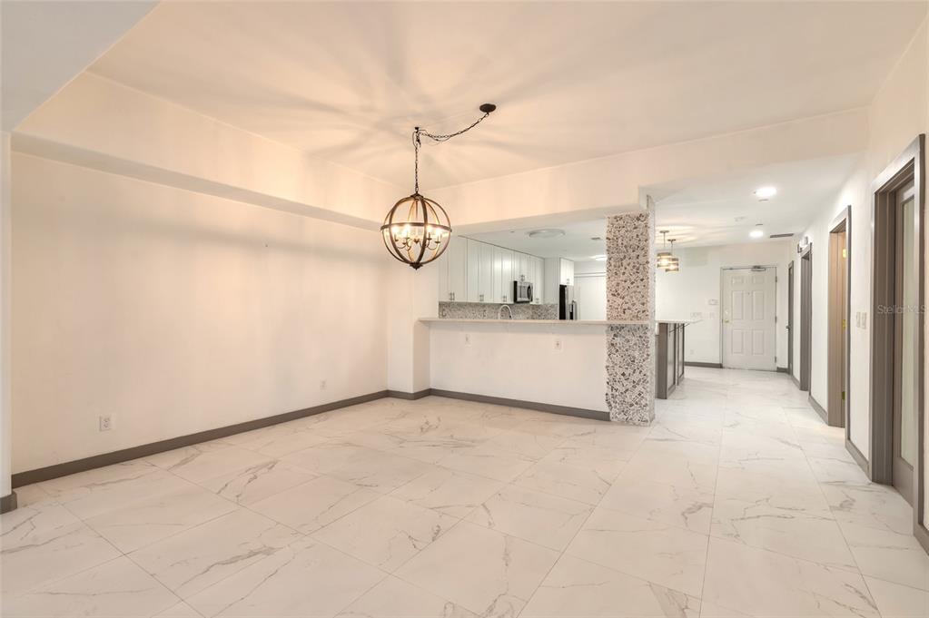 A dining area with white marble-look tile floors, a globe chandelier, and a kitchen pass-through — 424 LUNA BELLA LANE UNIT 416C, NEW SMYRNA BEACH, FL