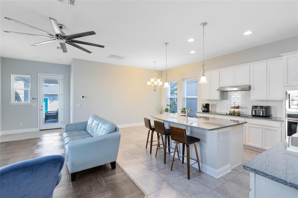 An open-concept kitchen with a granite island overlooks a living area and dining space — 7749 LAUREATE BOULEVARD, ORLANDO, FL