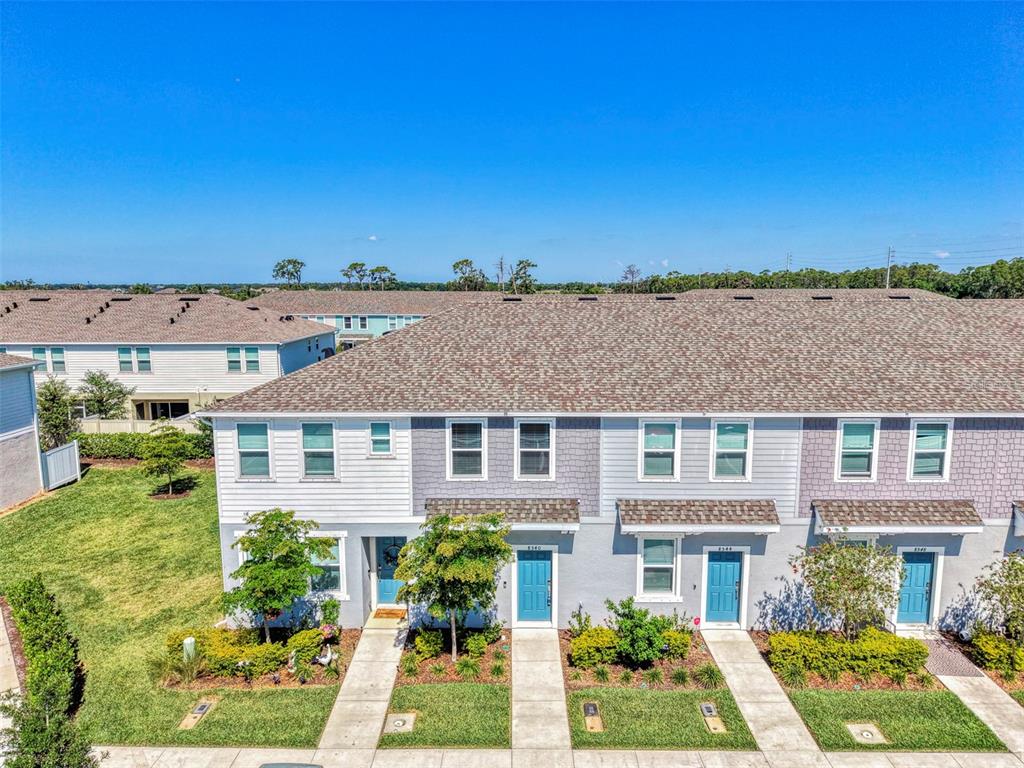 An exterior view of a row of two-story townhomes with gray siding and shingled roofs — 8540 DAYBREAK STREET, SARASOTA, FL