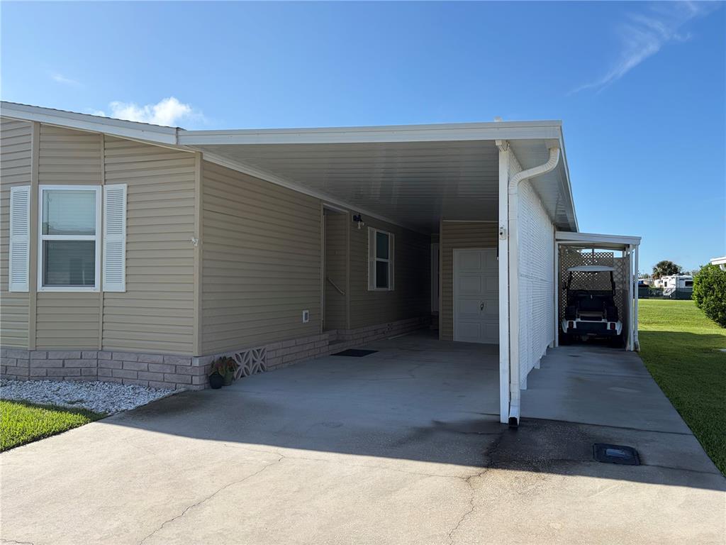 A tan mobile home features a concrete driveway, a covered carport, and a golf cart — 57 STRAPHMORE DRIVE, HAINES CITY, FL