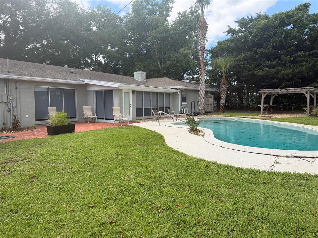 A backyard features a kidney-shaped swimming pool, a patio, and a single-story house with gray siding — 411 MONTICELLO DRIVE, ALTAMONTE SPRINGS, FL
