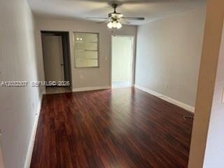 An empty room features dark wood-look flooring, a ceiling fan, and two doorways — 7601 Venetian St # 4, Miramar FL 33023, MIRAMAR, FL