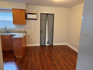 A kitchen with wood cabinets and hardwood floors leads to a doorway with screen doors — 7601 Venetian St # 4, Miramar FL 33023, MIRAMAR, FL
