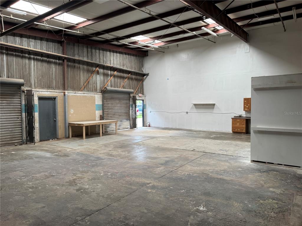 This industrial warehouse space features a concrete floor, exposed steel beams, and roll-up doors — 2920 W AIRPORT BOULEVARD UNIT 130, SANFORD, FL