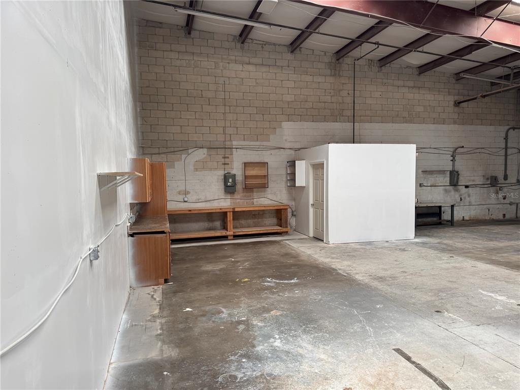 An industrial warehouse space features concrete block walls, a concrete floor, and a wooden workbench — 2920 W AIRPORT BOULEVARD UNIT 130, SANFORD, FL