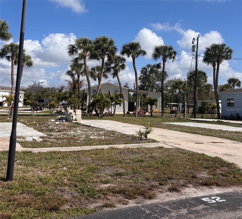 A vacant lot with a concrete pad and palm trees in a residential community — 7500 PARK POINTE DRIVE UNIT 52, ENGLEWOOD, FL