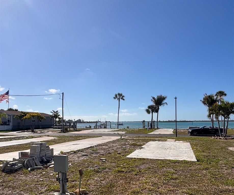 A vacant waterfront lot features concrete pads, palm trees, and a view of the bay — 7500 PARK POINTE DRIVE UNIT 52, ENGLEWOOD, FL