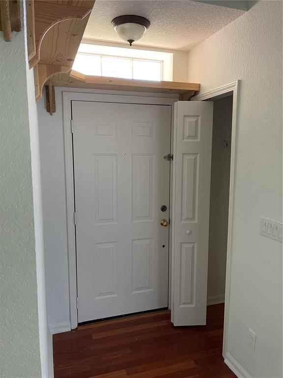 An entryway features a white front door, a bifold closet door, and a wooden shelf — 7617 BAY PORT ROAD UNIT 57, ORLANDO, FL
