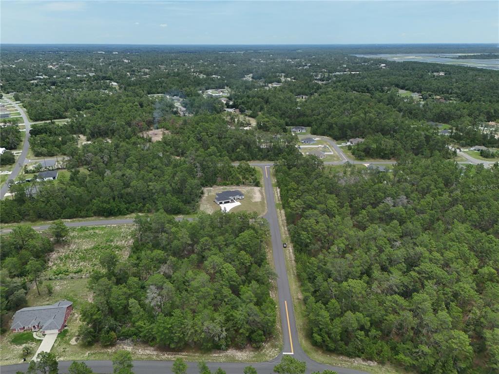 An aerial view shows a single-family home situated on a lot surrounded by dense forest — SW 40TH COURT, OCALA, FL