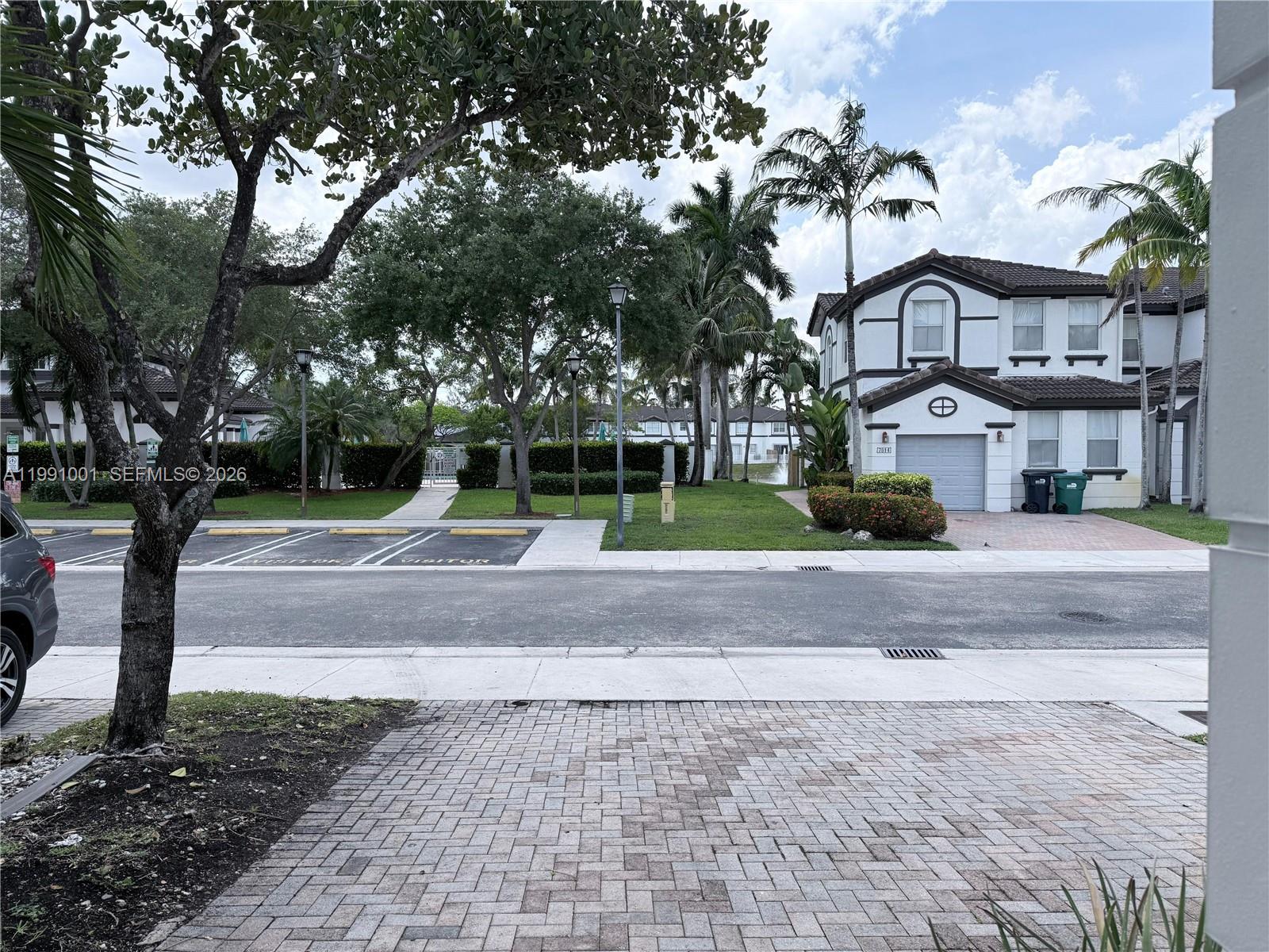A two-story residential building sits across a paved street with parking spaces and palm trees — 7809 NW 114th Path, Doral FL 33178, DORAL, FL