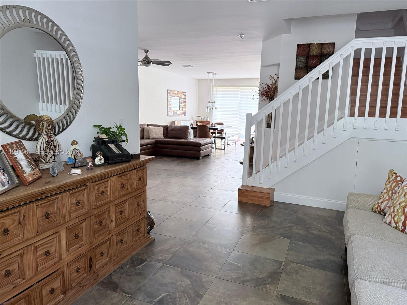 A living room features a wooden dresser, a staircase, and tile flooring — 7809 NW 114th Path, Doral FL 33178, DORAL, FL