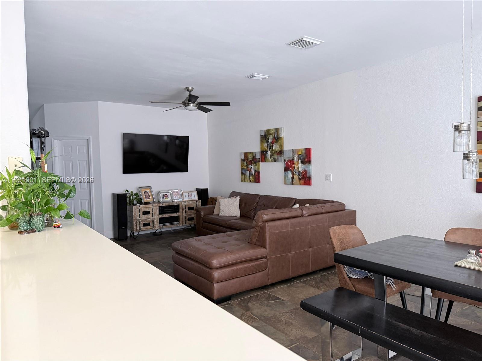A living room features a brown sectional sofa, tile floors, and a wall-mounted television — 7809 NW 114th Path, Doral FL 33178, DORAL, FL