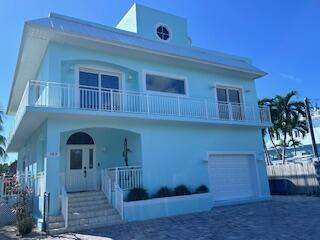 A light blue two-story house features a white balcony, a front door, and a garage — 103 Starfish Lane, Tavernier FL 33070, TAVERNIER, FL