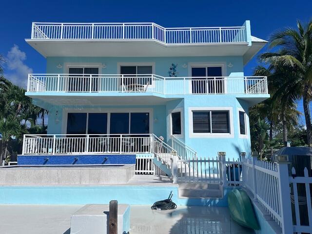 A three-story light blue house with white railings, a pool, and a dock — 103 Starfish Lane, Tavernier FL 33070, TAVERNIER, FL