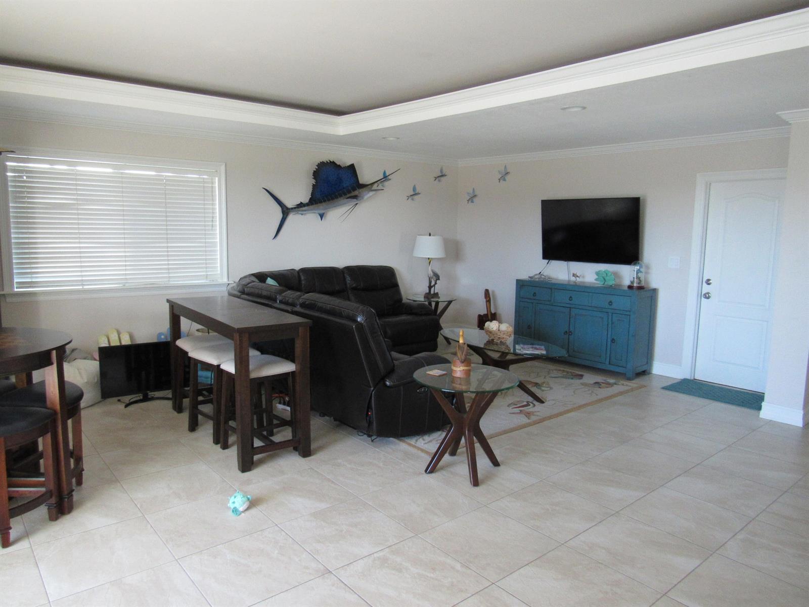 A living room features a dark leather sectional, a blue media console, and a sailfish mount — 103 Starfish Lane, Tavernier FL 33070, TAVERNIER, FL