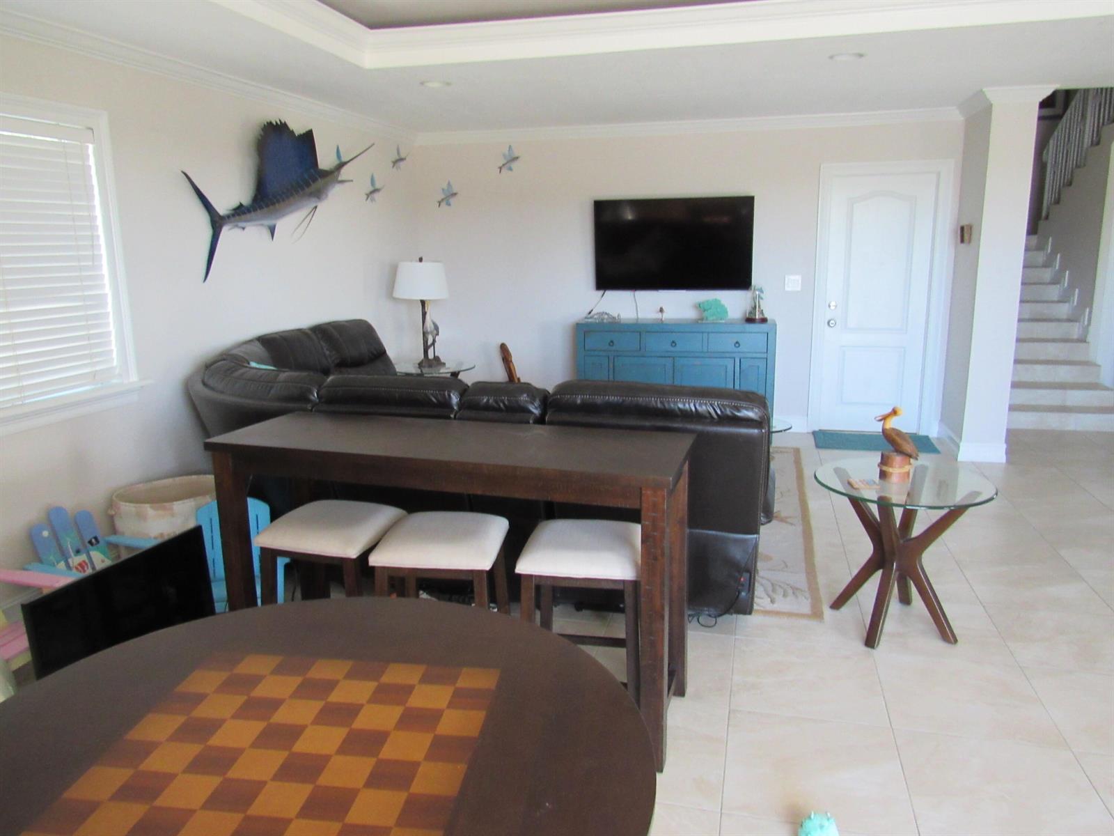 A living room features a dark leather sectional, a console table with stools, and a television — 103 Starfish Lane, Tavernier FL 33070, TAVERNIER, FL