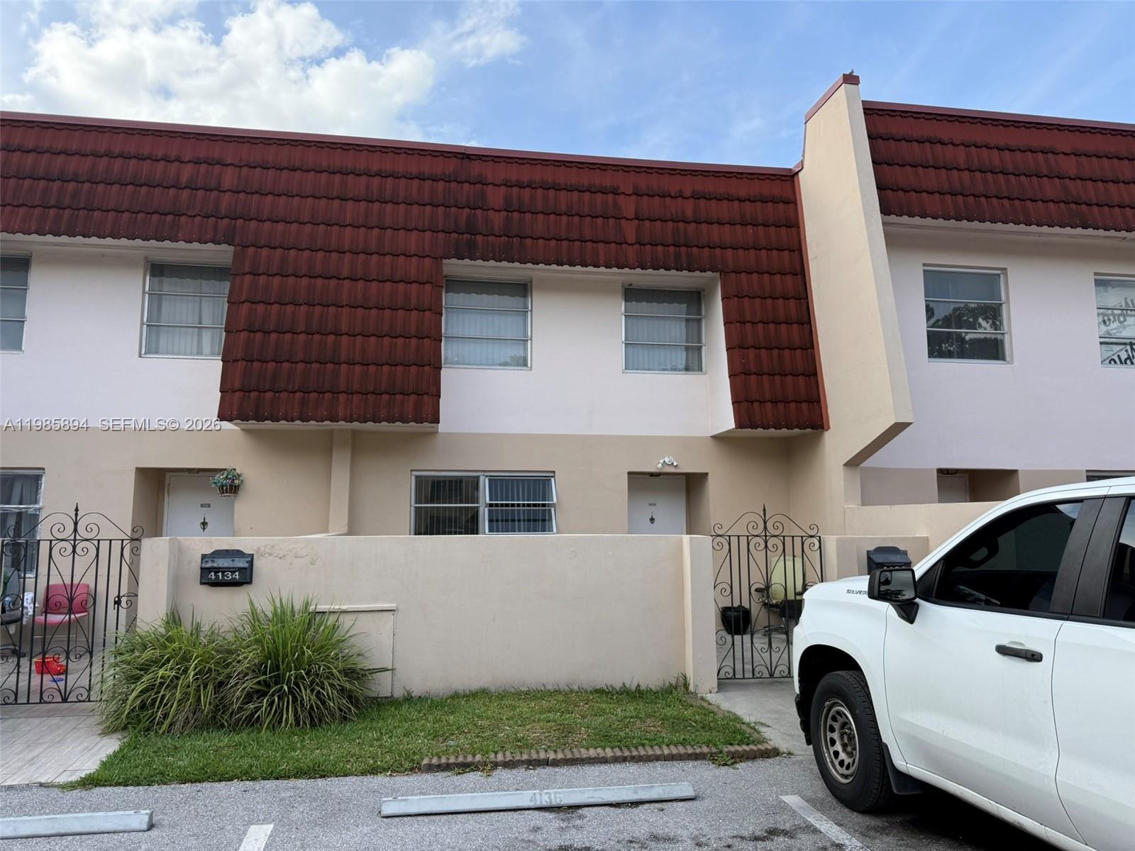 The exterior of two adjacent townhomes features beige stucco walls and a red mansard roof — 4136 Inverrary Dr # 15C, Lauderhill FL 33319, LAUDERHILL, FL