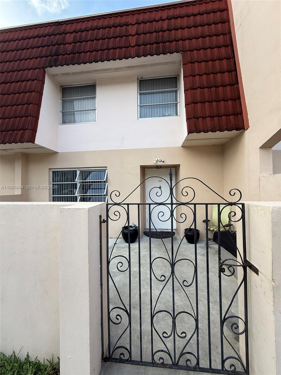 A two-story townhouse exterior features a red mansard roof, a gated courtyard, and white walls — 4136 Inverrary Dr # 15C, Lauderhill FL 33319, LAUDERHILL, FL