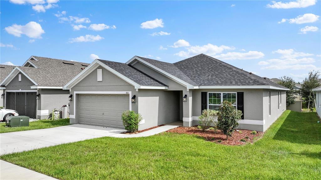 A gray, single-story suburban house with a two-car garage and a front lawn — 430 PANARO LANE, HAINES CITY, FL