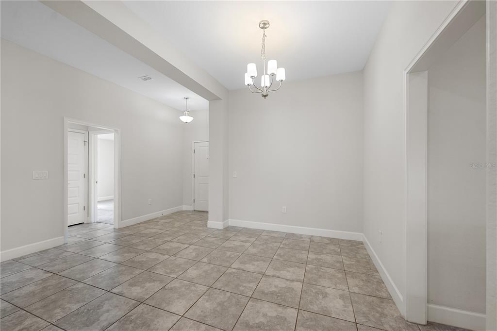 A dining area with light gray walls, tile flooring, and a central chandelier — 430 PANARO LANE, HAINES CITY, FL