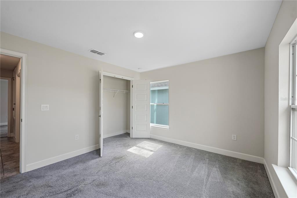 A bedroom with light-colored walls, gray carpeting, a closet, and two windows — 430 PANARO LANE, HAINES CITY, FL