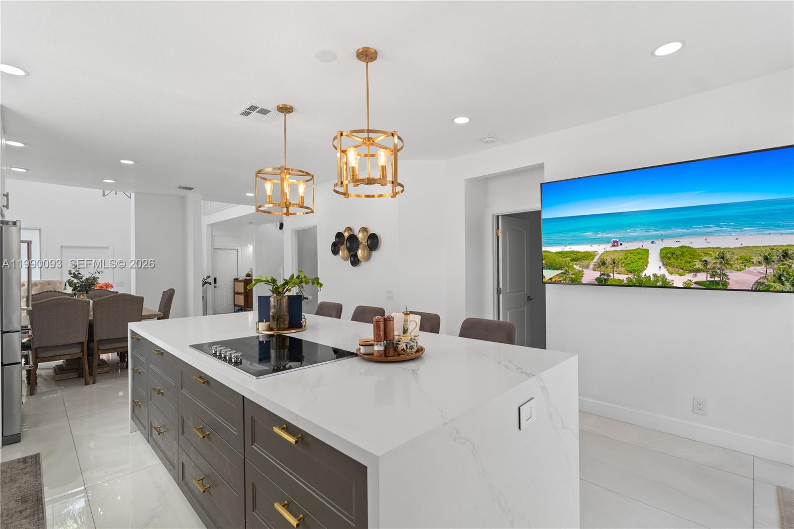 A kitchen island with a cooktop and gray cabinets sits beneath two gold pendant lights — 1500 Canary Island Dr, Weston FL 33327, WESTON, FL