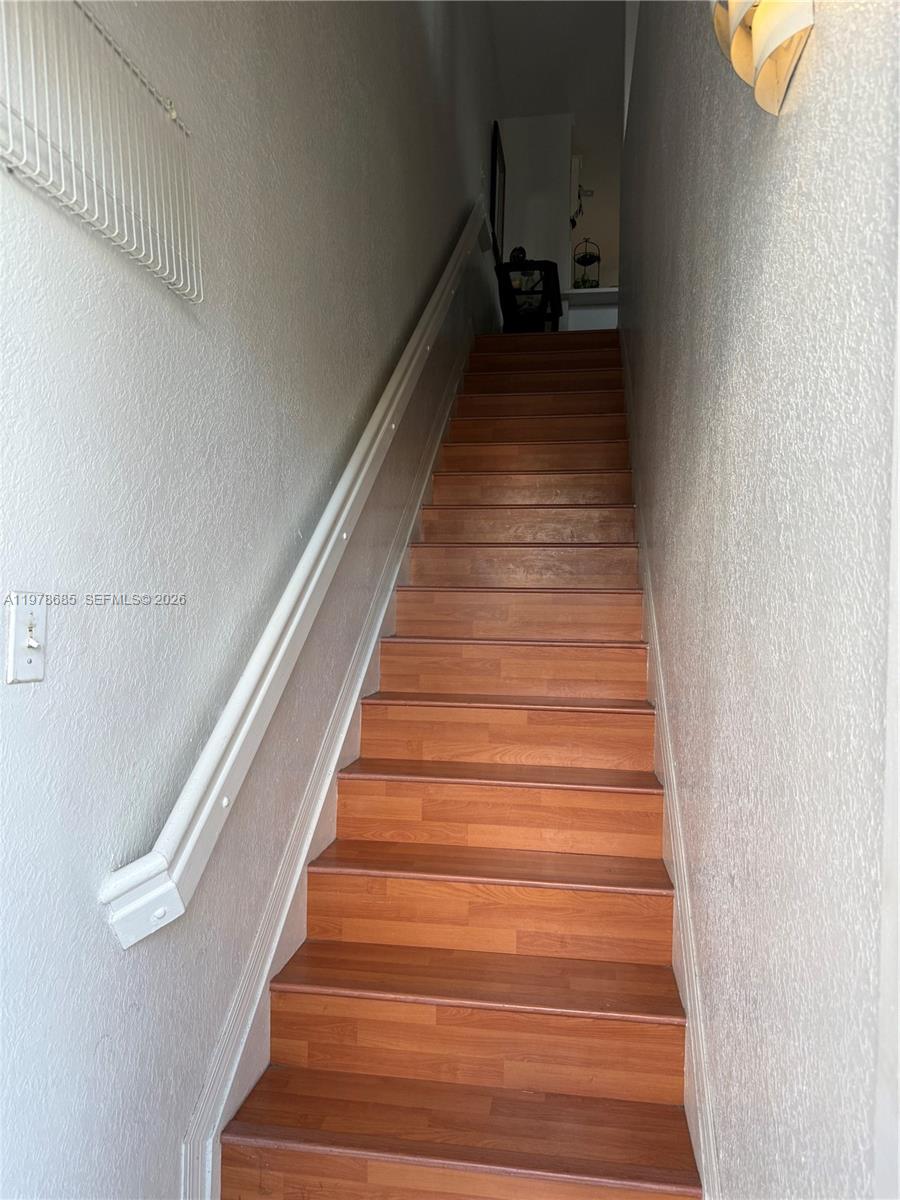 A straight wooden staircase with a white handrail leads upward between two plain walls — 5605 NW 109th Ave # 76, Doral FL 33178, DORAL, FL