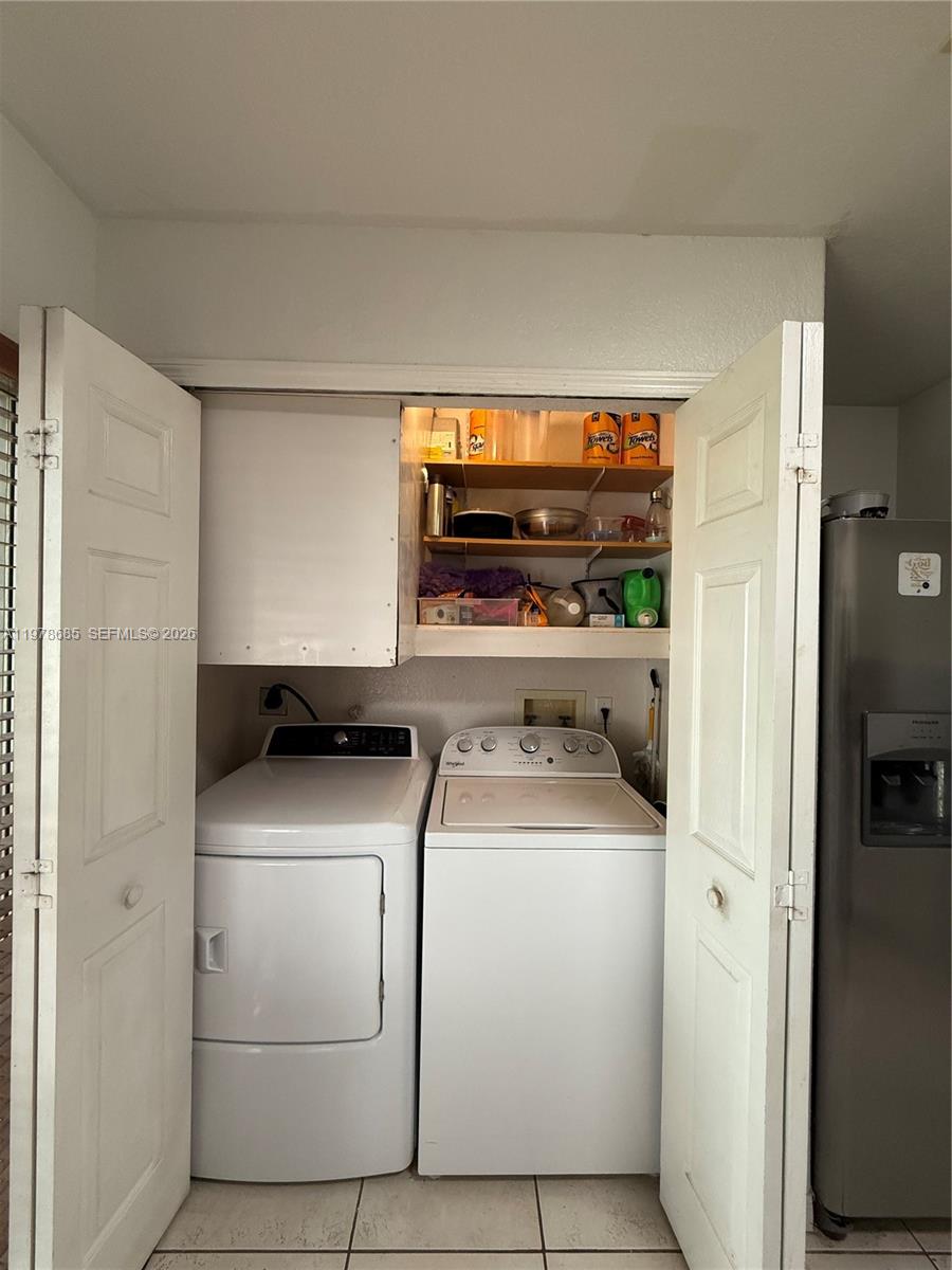 A laundry closet features a white washer and dryer with open shelving above — 5605 NW 109th Ave # 76, Doral FL 33178, DORAL, FL