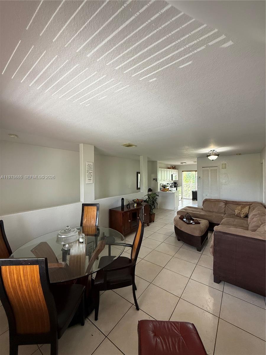 An open-concept living and dining area features tile flooring, a glass table, and a sectional — 5605 NW 109th Ave # 76, Doral FL 33178, DORAL, FL