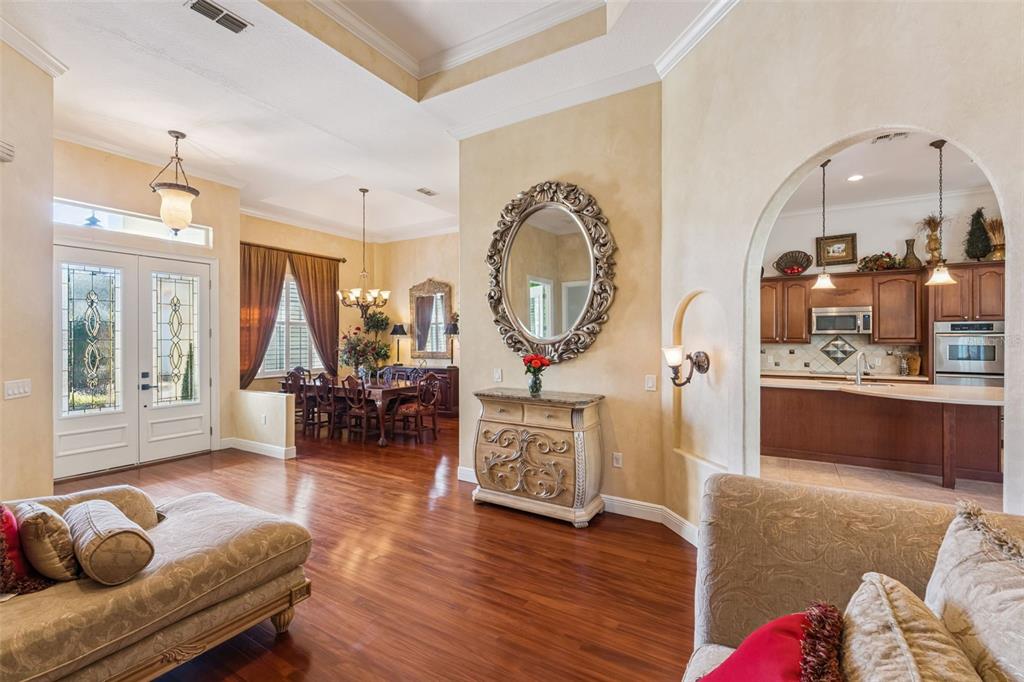 A living room with hardwood floors, a dining area, and an arched entryway to the kitchen — 814 MIAMI SPRINGS DRIVE, LONGWOOD, FL