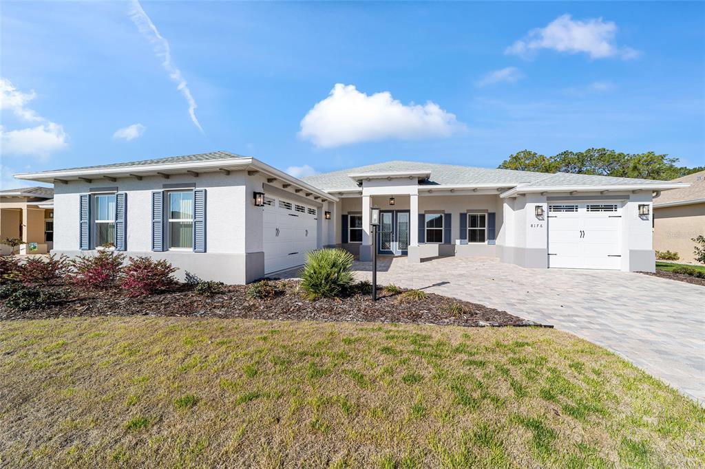 A single-story house with a light-colored stucco exterior, two garage doors, and a paved driveway — 8176 SW 98TH TERRACE ROAD, OCALA, FL