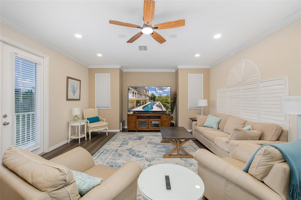 A living room features a television, beige sofas, a ceiling fan, and a patterned rug — 3020 SHEPPARDS CROOK COURT, HOLIDAY, FL