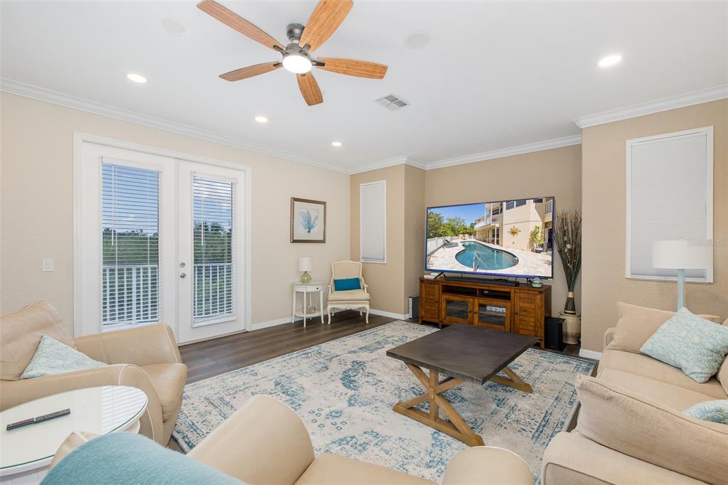A living room features a ceiling fan, a large television, and a patterned area rug — 3020 SHEPPARDS CROOK COURT, HOLIDAY, FL