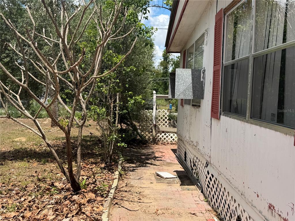 A side view of a mobile home exterior with a window air conditioning unit — 10006 CAUSEY PL, THONOTOSASSA, FL