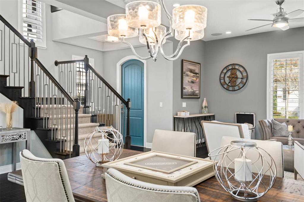 A dining area features a wooden table, upholstered chairs, a chandelier, and a staircase — 8801 FOUNTAIN PALM ALLEY, WINTER GARDEN, FL