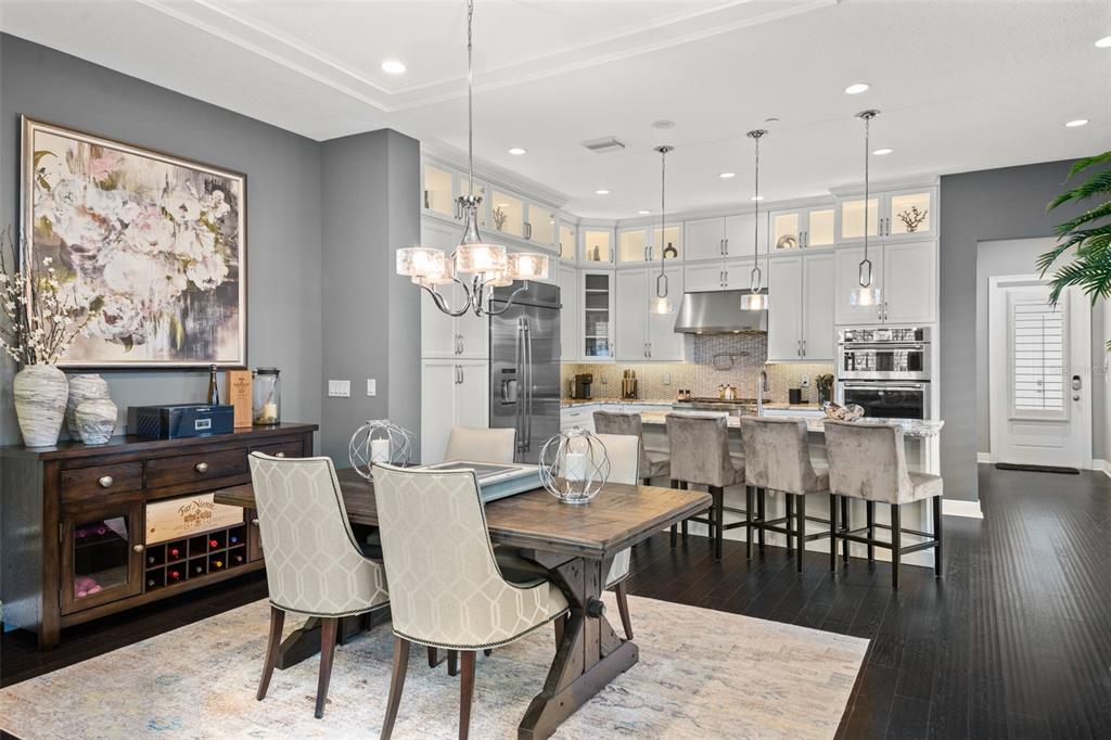 A dining area with a wooden table and chairs sits adjacent to a modern kitchen — 8801 FOUNTAIN PALM ALLEY, WINTER GARDEN, FL