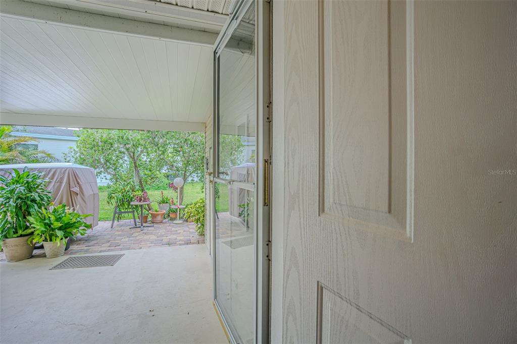 A view from inside a doorway looking out onto a covered patio and yard — 37654 NEUKOM AVENUE, ZEPHYRHILLS, FL