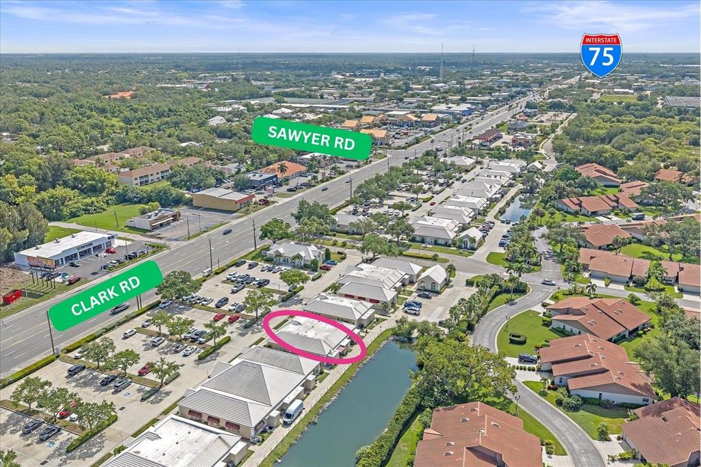 An aerial view shows a commercial building complex with a parking lot and a pond — 3900 CLARK ROAD UNIT D2, SARASOTA, FL