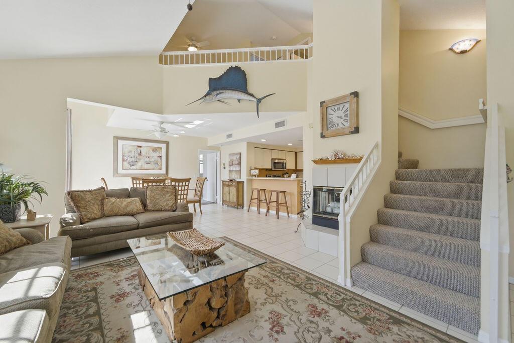 A living room with a fireplace, stairs, and a dining area in an open floor plan — 1509 Mizzenmast Way, Jupiter FL 33477, JUPITER, FL