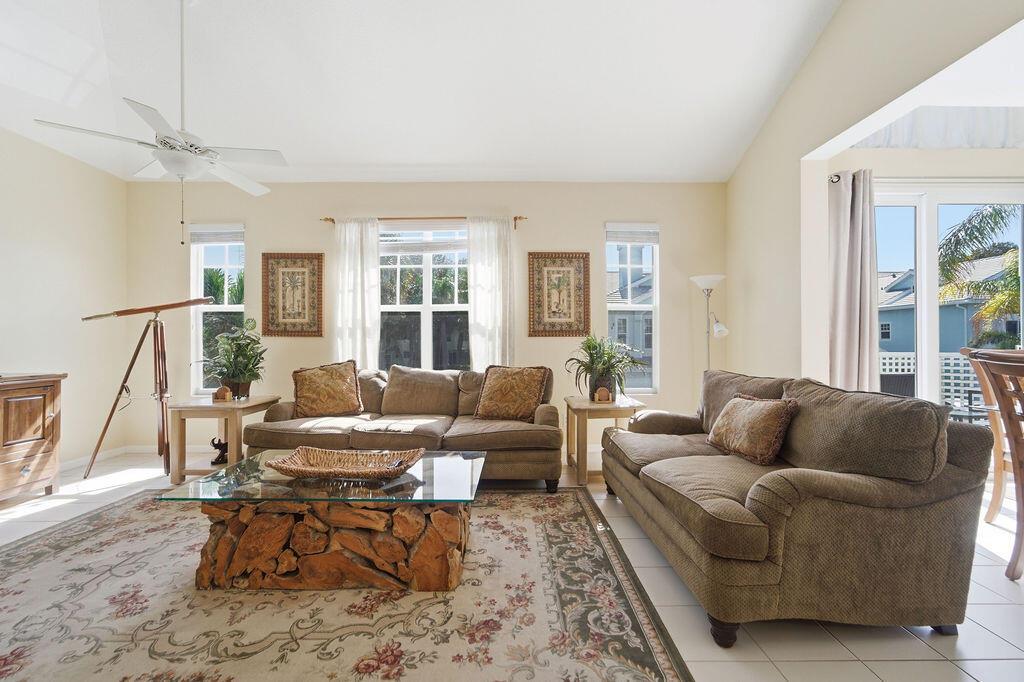 A living room features two brown sofas, a glass-topped root coffee table, and a telescope — 1509 Mizzenmast Way, Jupiter FL 33477, JUPITER, FL