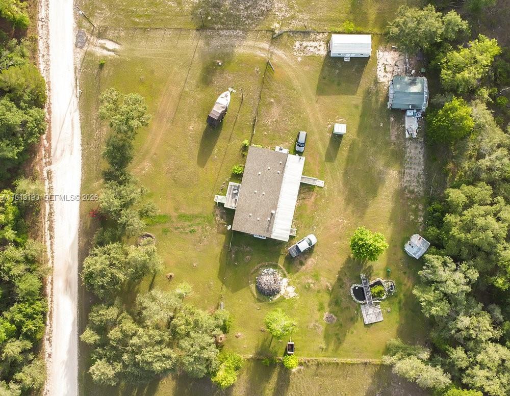 An aerial view shows a house with a metal roof, outbuildings, and a boat parked nearby — 12531 NE 18 St, Williston FL 32696, WILLISTON, FL