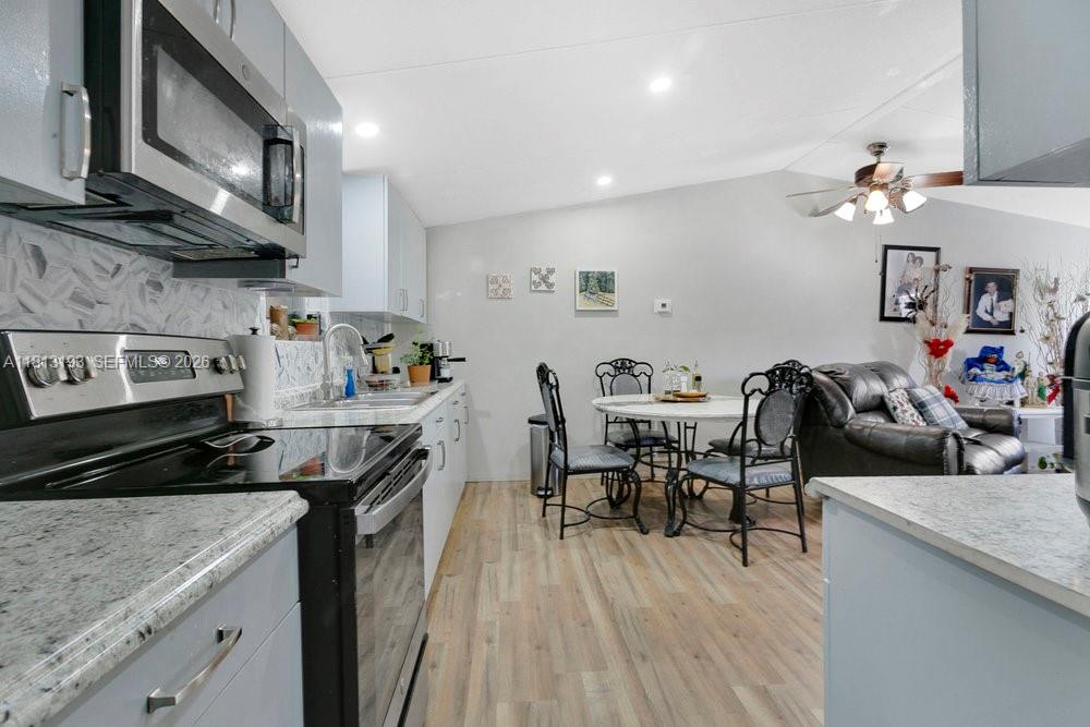A kitchen with light gray cabinets and stainless steel appliances opens into a dining area — 12531 NE 18 St, Williston FL 32696, WILLISTON, FL