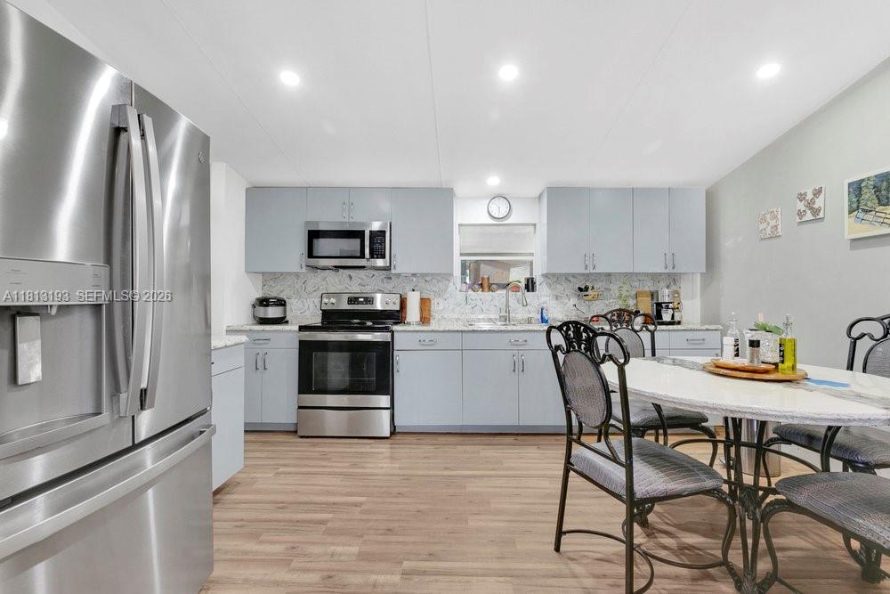 A kitchen features light blue cabinets, stainless steel appliances, and a dining table with chairs — 12531 NE 18 St, Williston FL 32696, WILLISTON, FL
