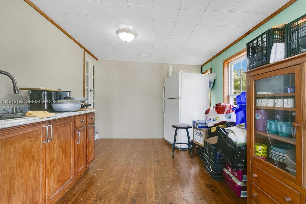 A kitchen features wood cabinets, a granite countertop, a white refrigerator, and wood flooring — 12531 NE 18 St, Williston FL 32696, WILLISTON, FL