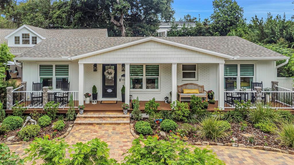 A large oak tree stands in a front yard with a swing and paved driveway — 411 ROEBLING ROAD S, BELLEAIR, FL